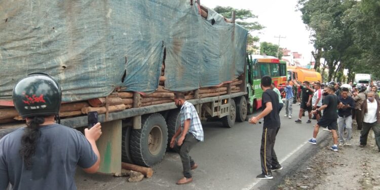 Bus Penumpang Pariwisata Laga Kambing Dengan Tronton Pengangkut Kayu Balok